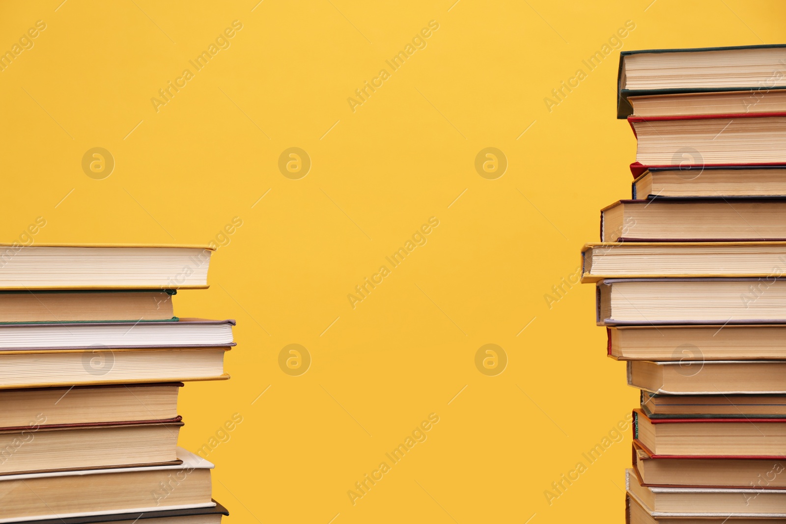 Photo of Many hardcover books on orange background, space for text. Library material