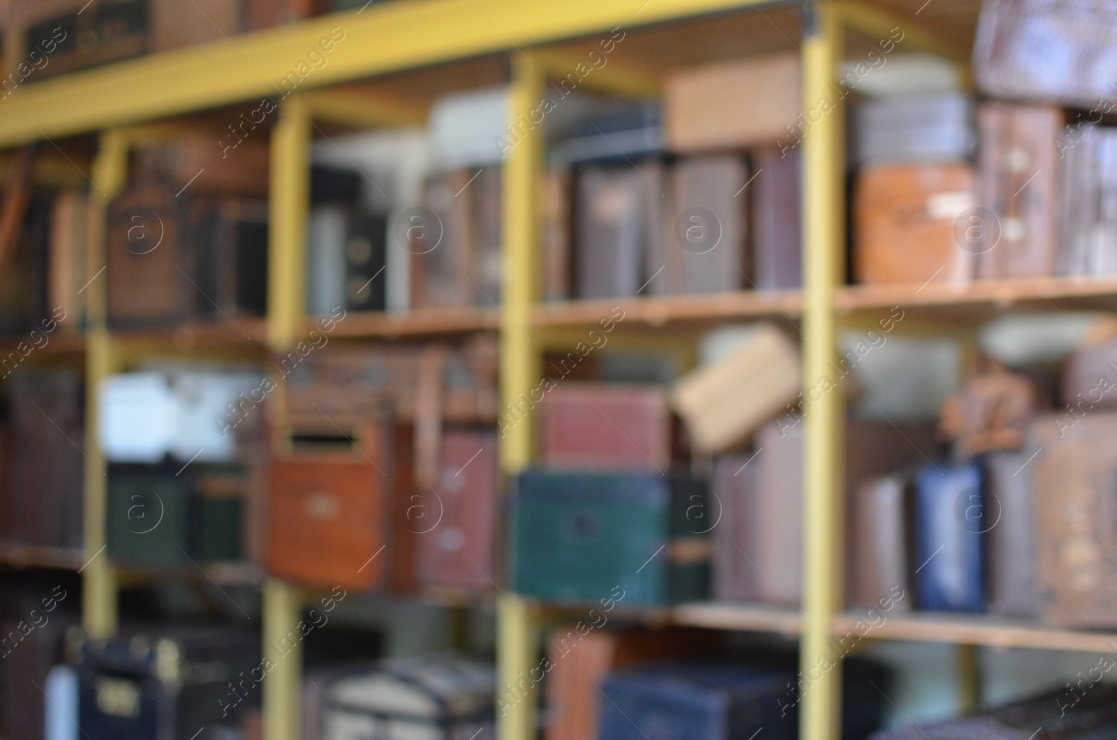 Photo of Blurred view of retro suitcases on shelves indoors