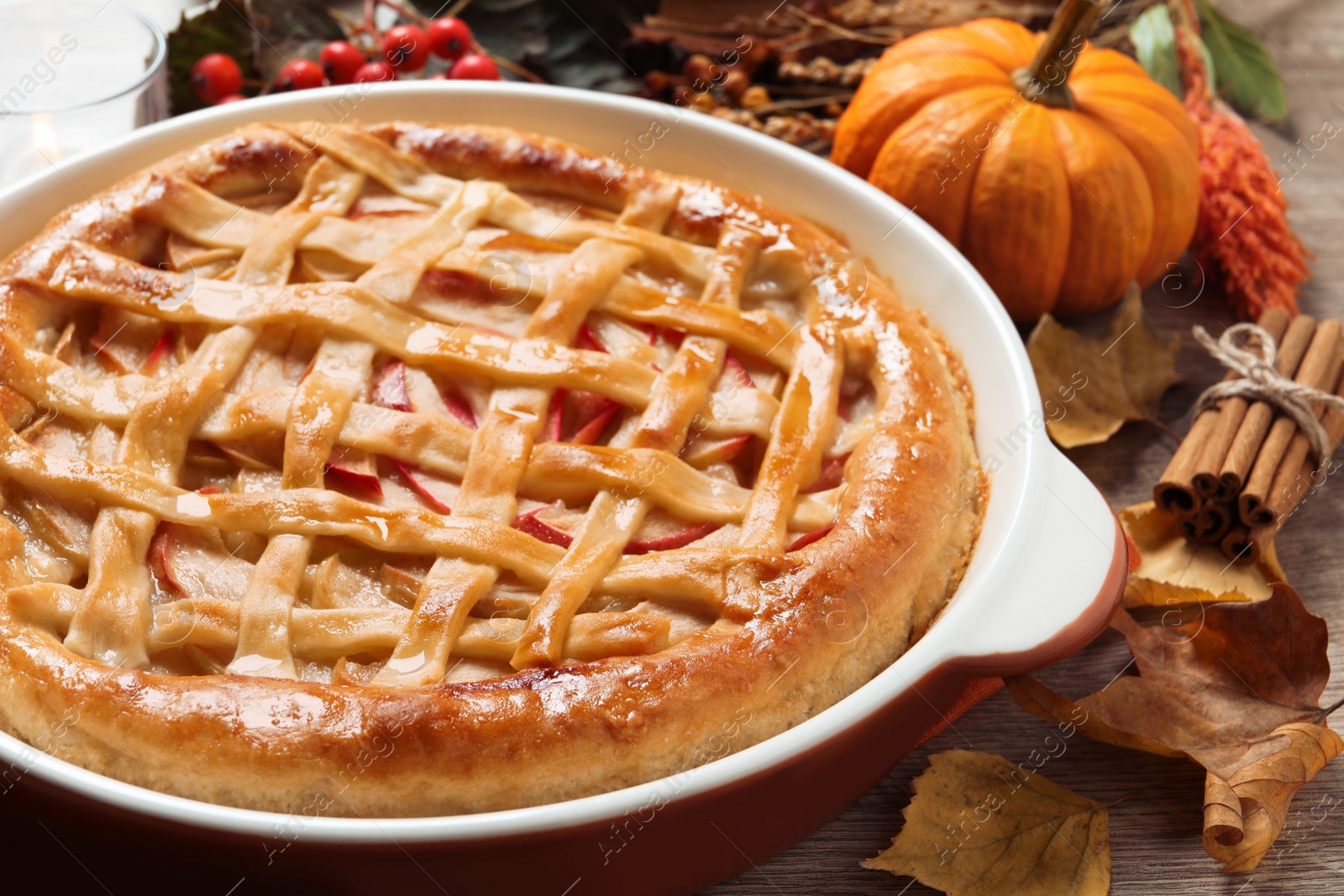 Photo of Delicious homemade apple pie and autumn decor on wooden table, closeup. Thanksgiving Day celebration