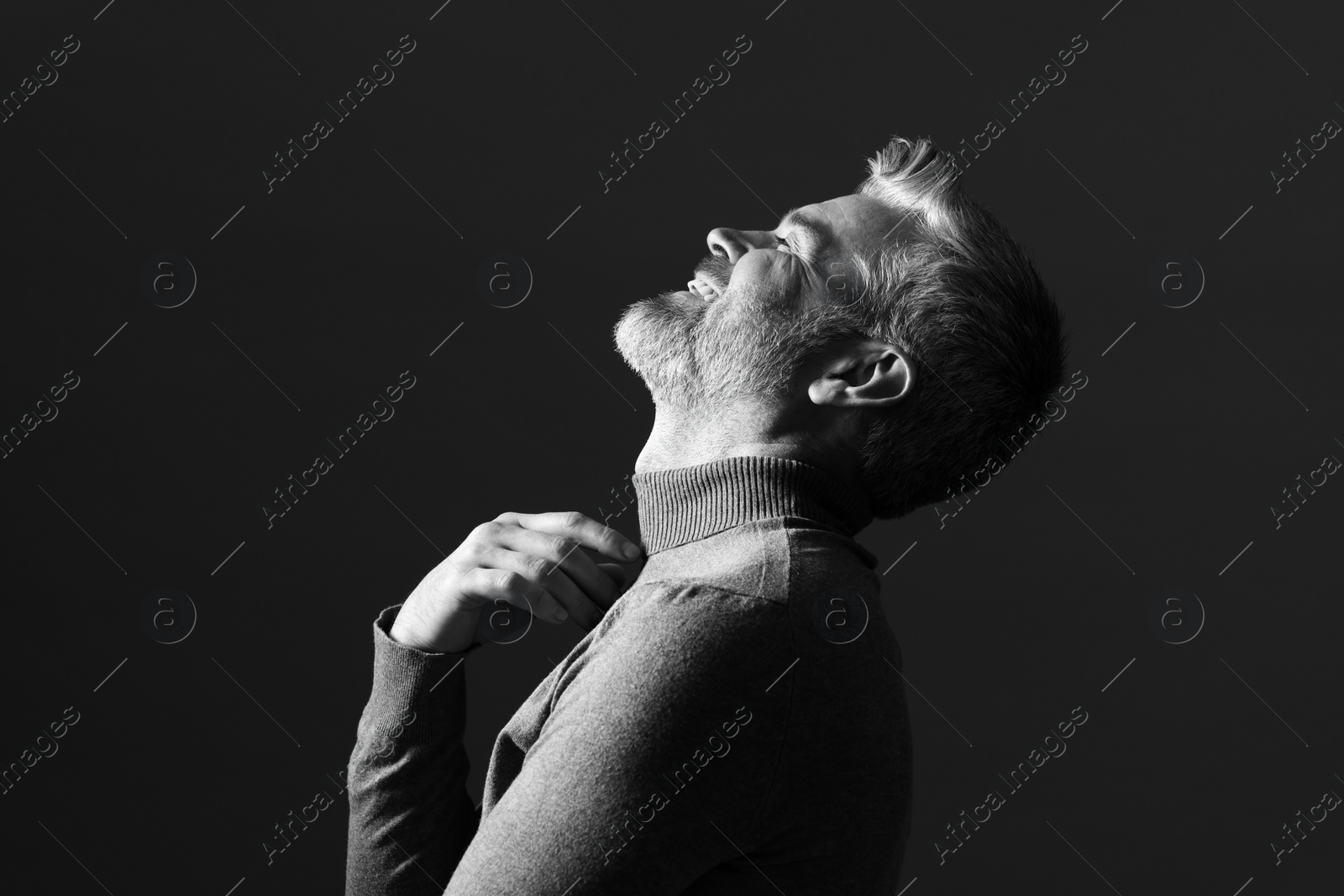 Photo of Portrait of smiling man on dark background. Black and white effect