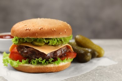 Photo of Tasty hamburger with patty and pickles on light grey table, closeup. Space for text