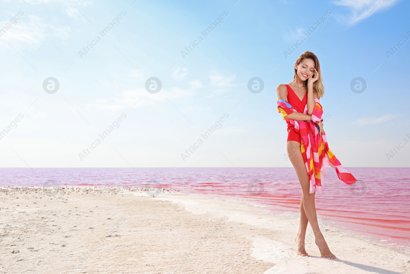 Photo of Beautiful woman in swimsuit posing near pink lake on sunny day