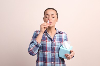 Photo of Woman using nasal spray on beige background