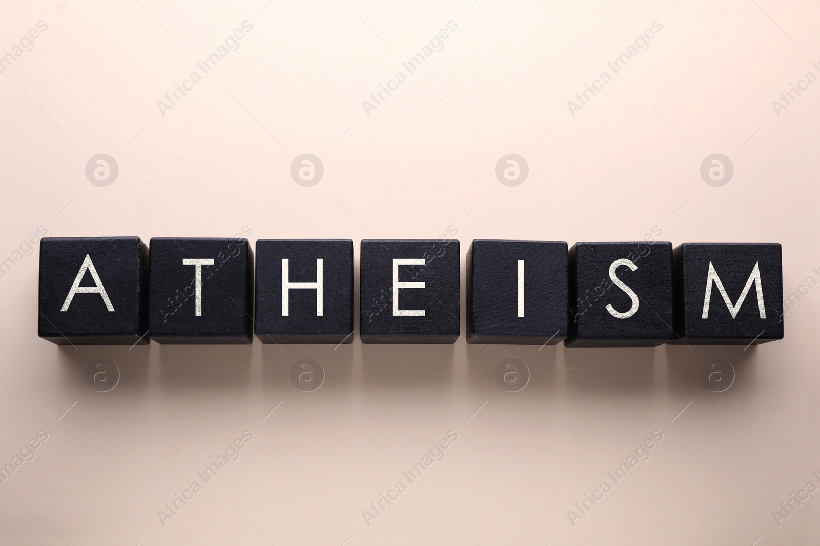 Image of Word Atheism made of black wooden squares with letters on beige background, top view