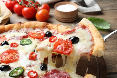 Photo of Taking slice of delicious pizza Diablo on wooden table, closeup