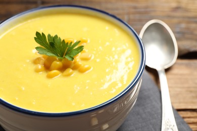 Delicious creamy corn soup served on wooden table, closeup