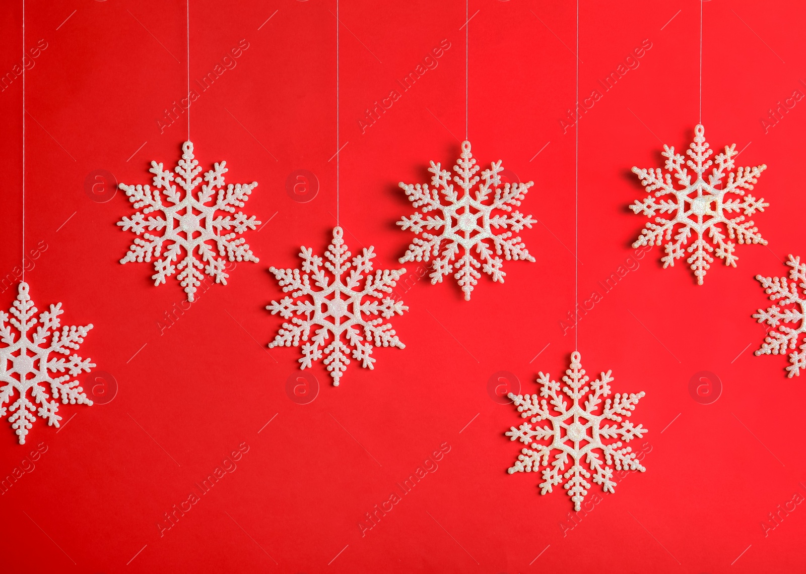 Photo of Beautiful decorative snowflakes hanging on red background