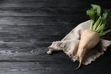 Fresh sugar beet with leaves on black wooden table. Space for text