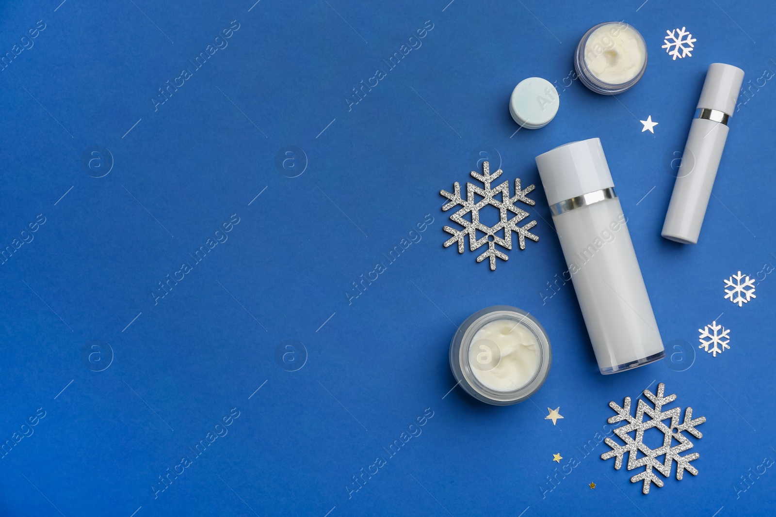 Photo of Flat lay composition with cosmetic products on blue background, space for text. Winter care