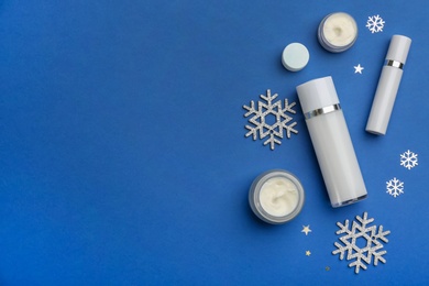 Photo of Flat lay composition with cosmetic products on blue background, space for text. Winter care