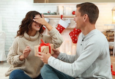 Man presenting Christmas gift to his girlfriend at home 