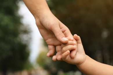 Photo of Daughter holding mother's hand in park, closeup. Happy family