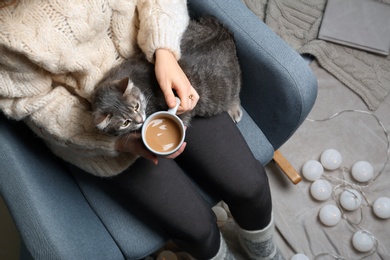 Photo of Woman in warm sweater with cute cat sitting in armchair, top view