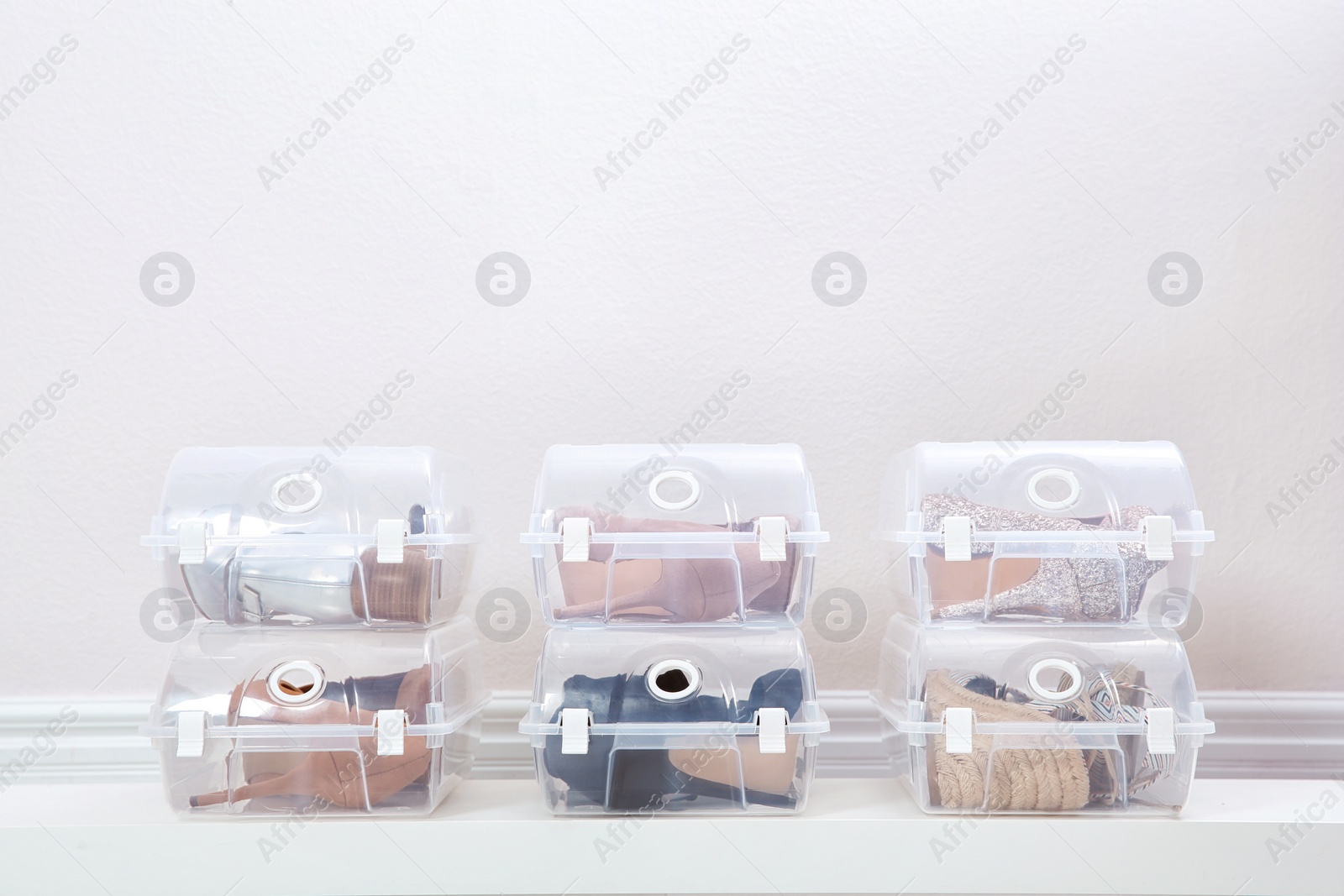 Photo of Shoes in plastic boxes near light wall. Storage organization