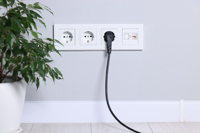 Power sockets and electric plug on grey wall