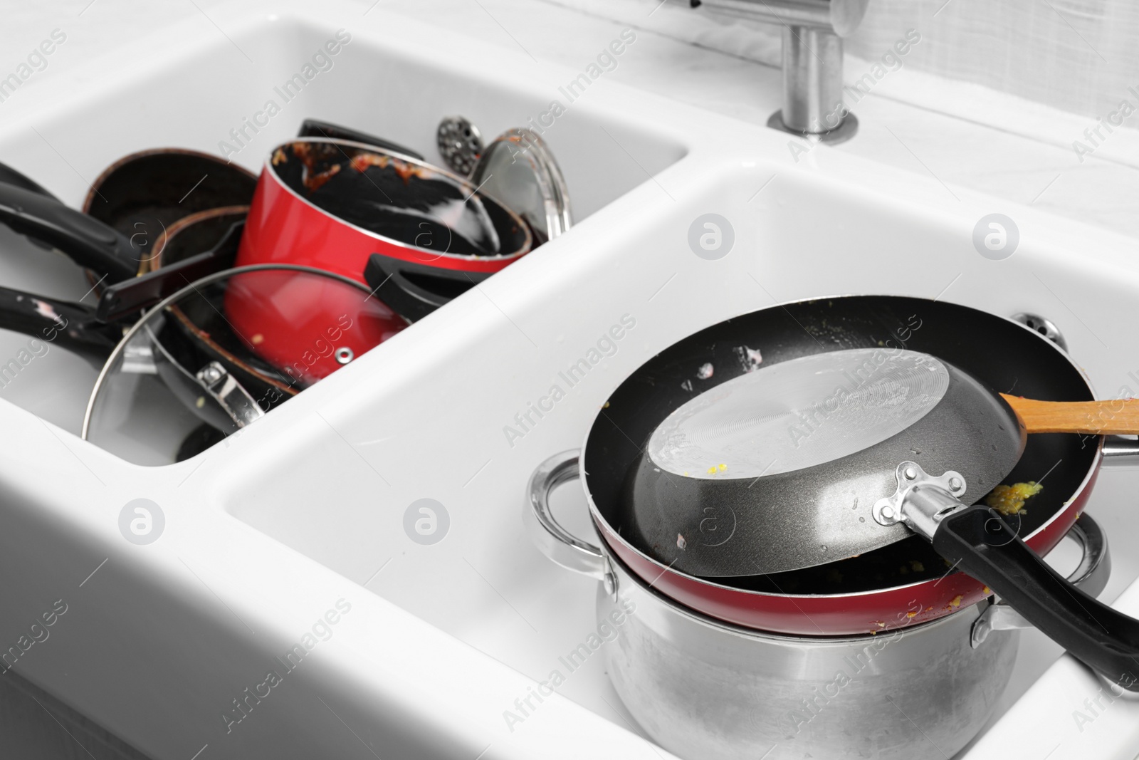 Photo of Stacks of dirty kitchenware in white sink