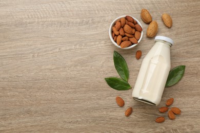 Delicious almond milk and nuts on wooden table, flat lay. Space for text