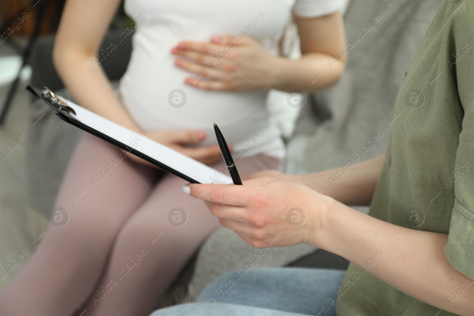 Photo of Doula working with pregnant woman indoors, closeup. Preparation for child birth