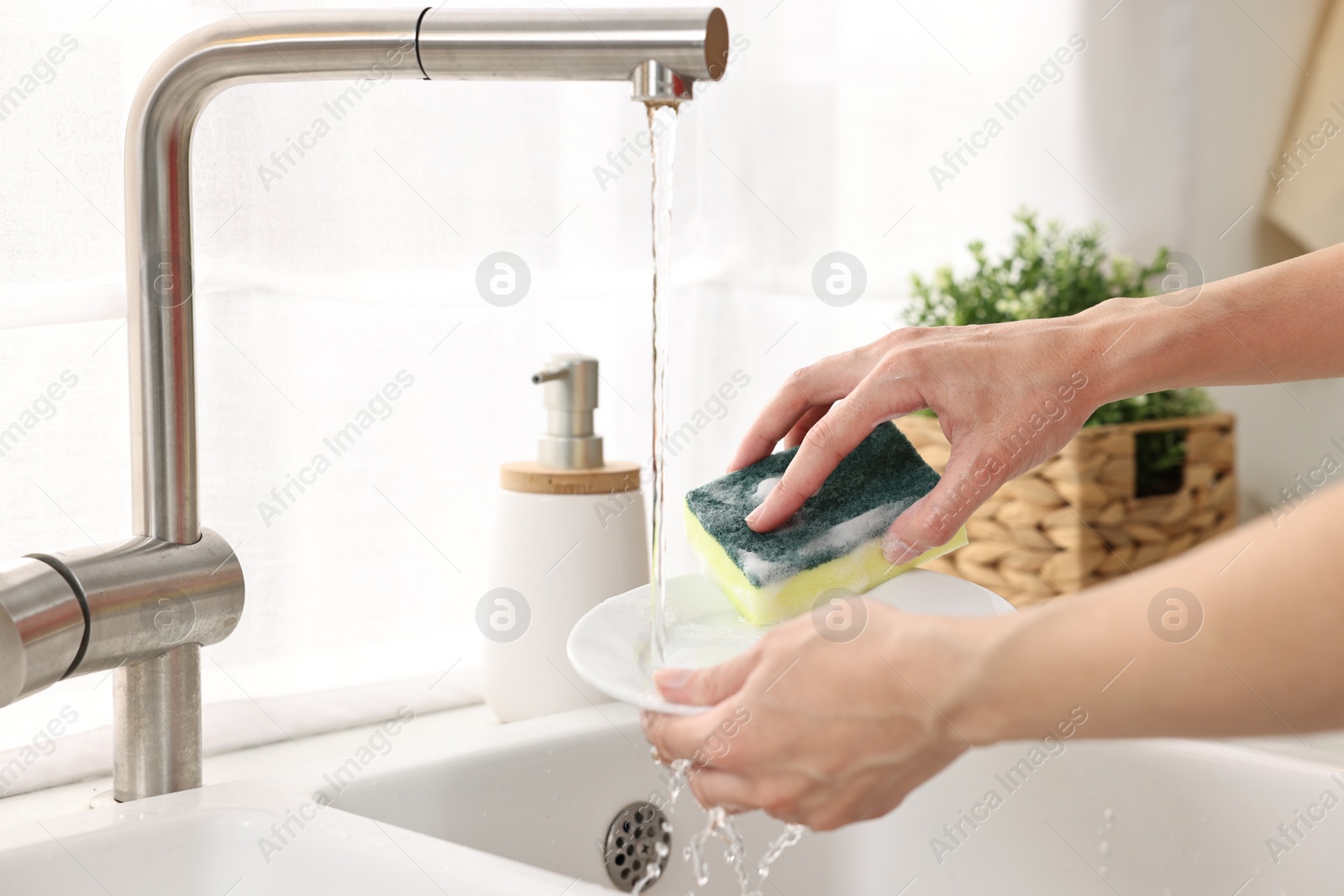 Photo of Woman washing dishes in kitchen sink, closeup. Cleaning chores