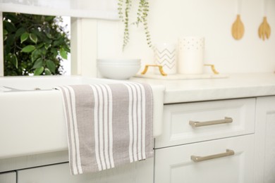Photo of Clean towel hanging on white sink in kitchen