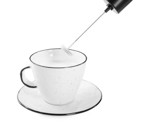 Photo of Whisking milk in cup with mini mixer (frother wand) isolated on white