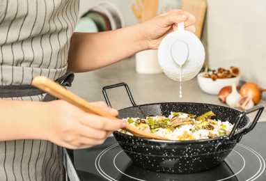 Photo of Woman cooking delicious risotto, closeup. Tasty recipe