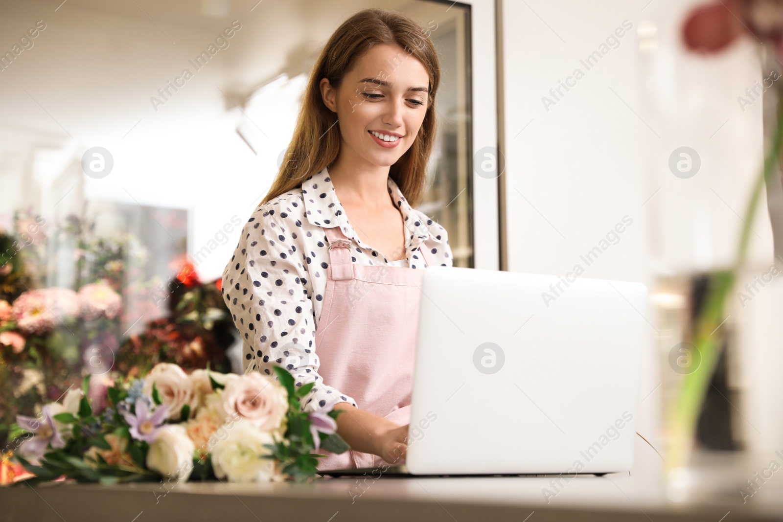 Photo of Professional female florist using laptop at workplace