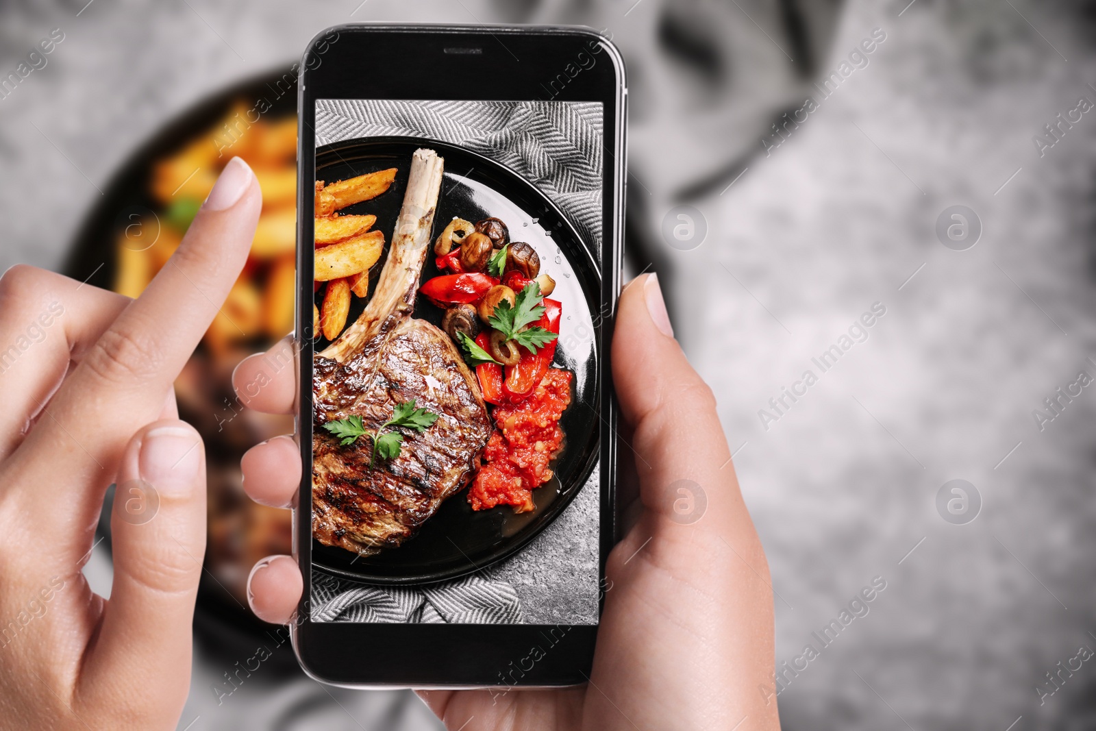 Image of Blogger taking picture of delicious grilled ribeye at table, closeup. Food photography