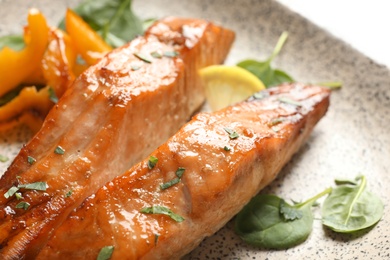 Photo of Tasty cooked salmon with lemon on plate, closeup