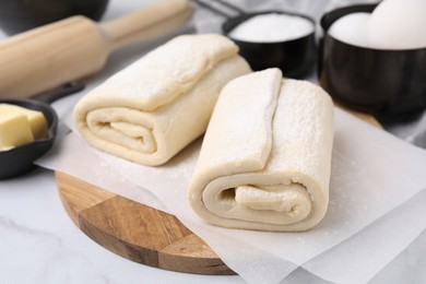 Raw puff pastry dough on white marble table, closeup