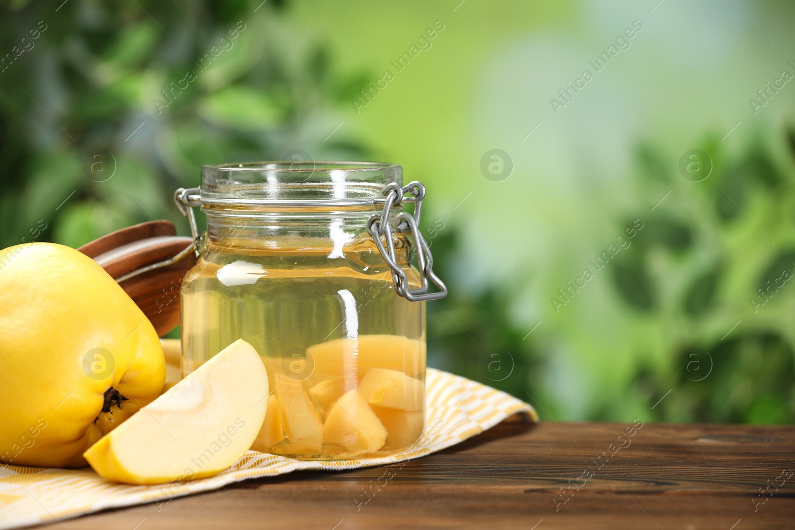Photo of Delicious quince drink and fresh fruits on wooden table against blurred background. Space for text