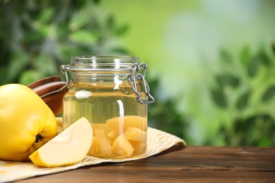 Delicious quince drink and fresh fruits on wooden table against blurred background. Space for text