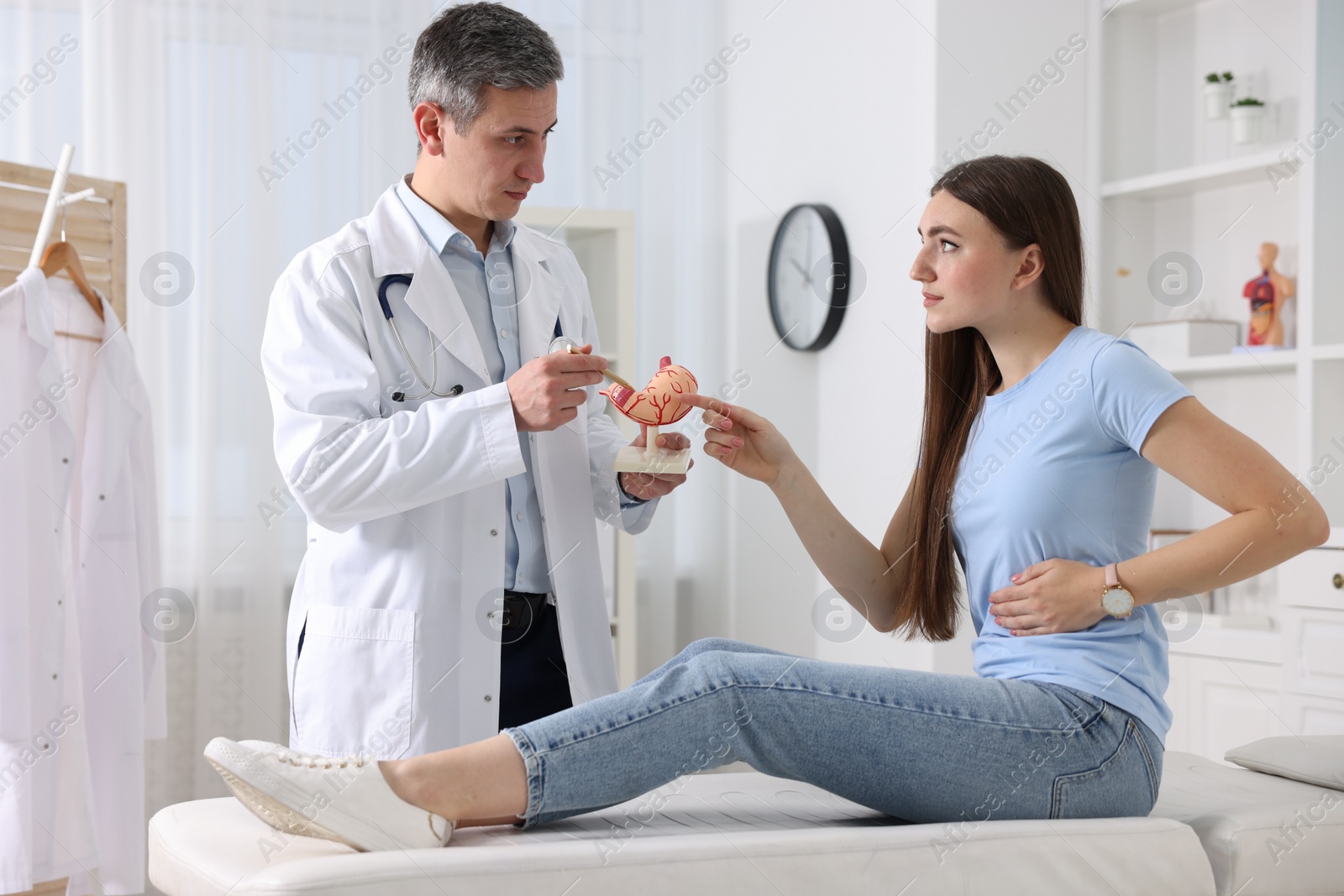 Photo of Gastroenterologist with human stomach model consulting patient in clinic