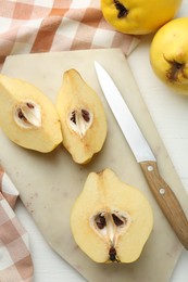 Photo of Tasty ripe quinces and knife on white wooden table, flat lay