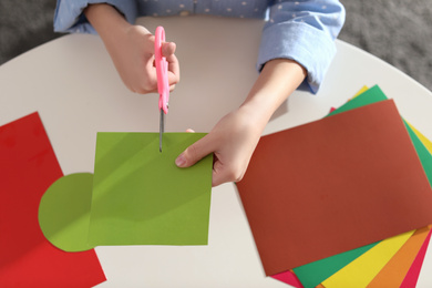 Little girl making greeting card at table indoors, top view. Creative hobby