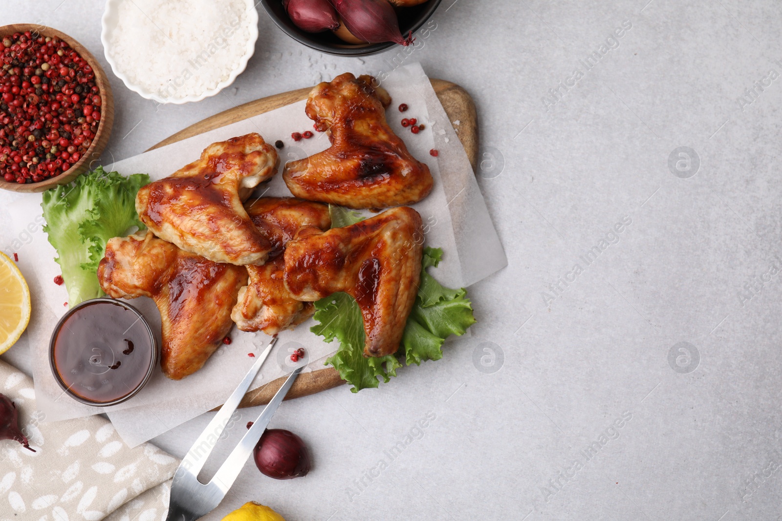 Photo of Flat lay composition with marinade, chicken wings and other products on light table. Space for text