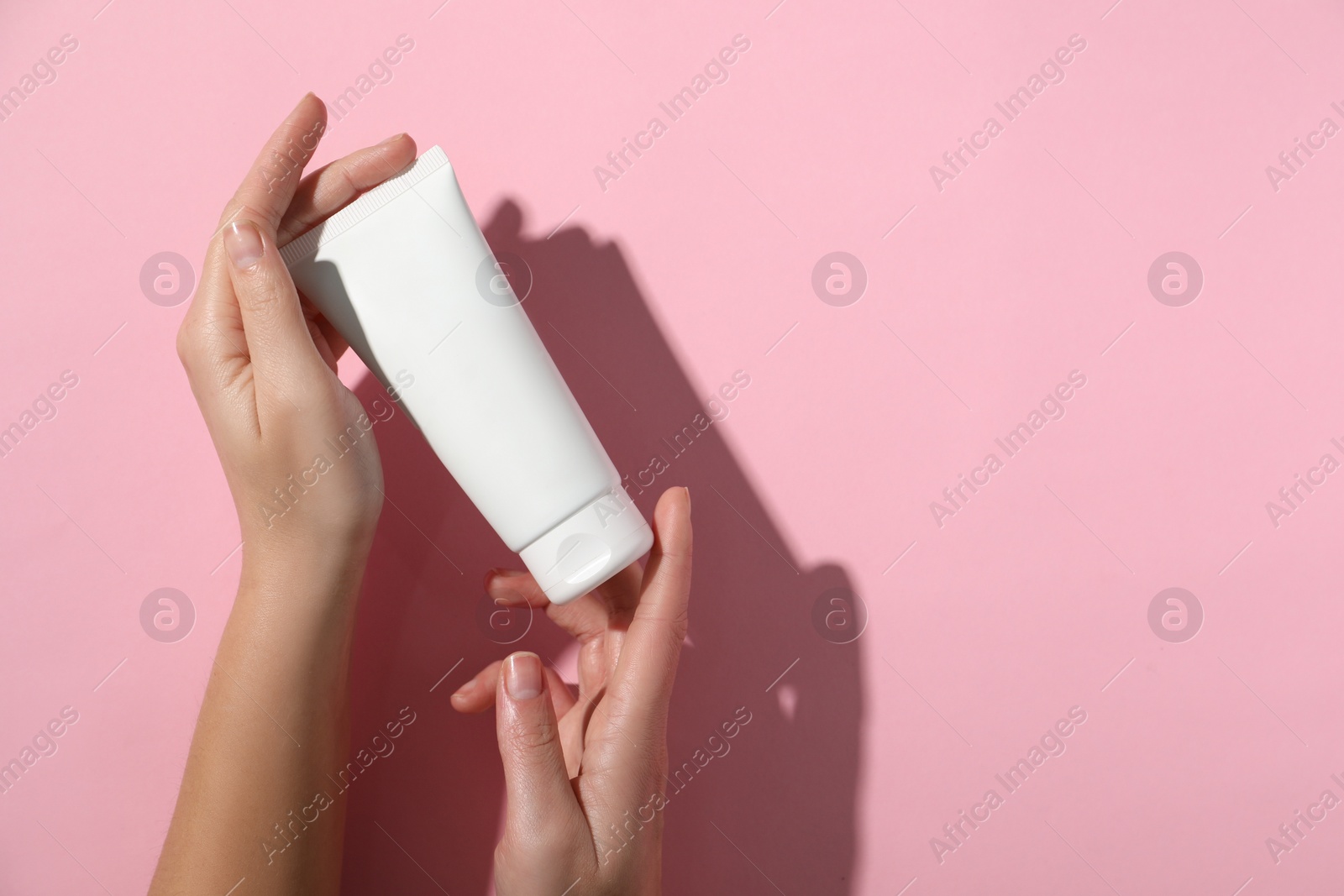 Photo of Woman with tube of hand cream on pink background, top view. Space for text