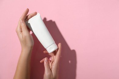 Photo of Woman with tube of hand cream on pink background, top view. Space for text