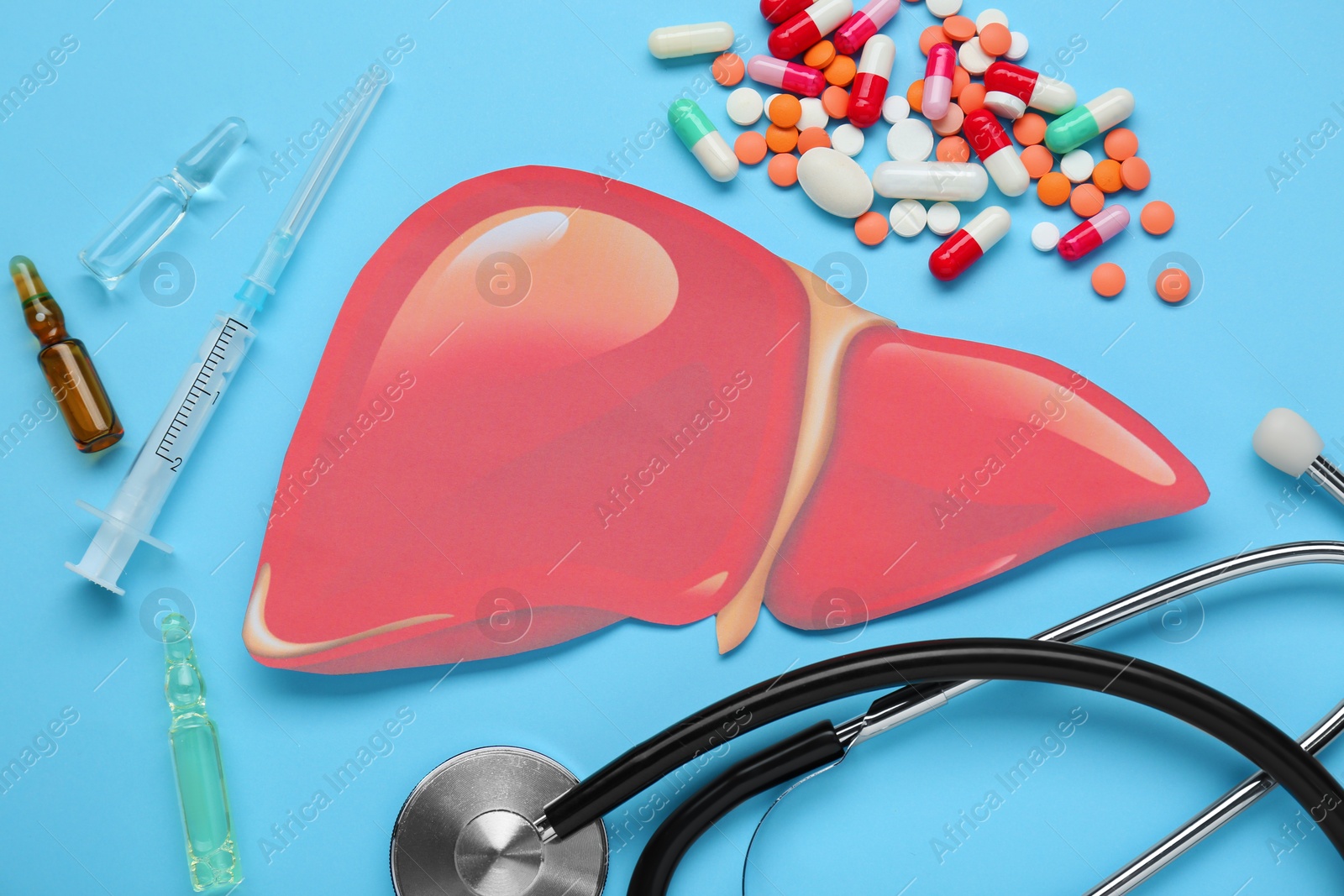 Photo of Paper liver and medical supplies on light blue background, flat lay. Hepatitis treatment