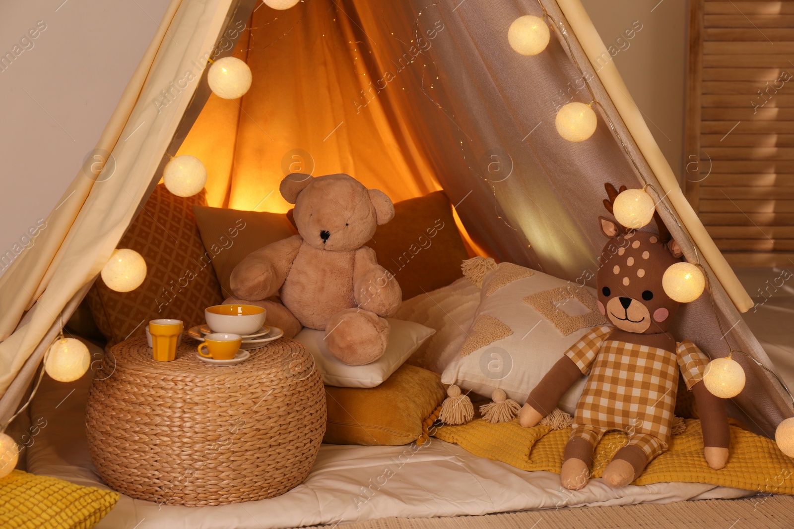 Photo of Play tent with toys and pillows indoors, closeup. Modern children's room interior