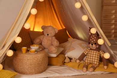 Play tent with toys and pillows indoors, closeup. Modern children's room interior