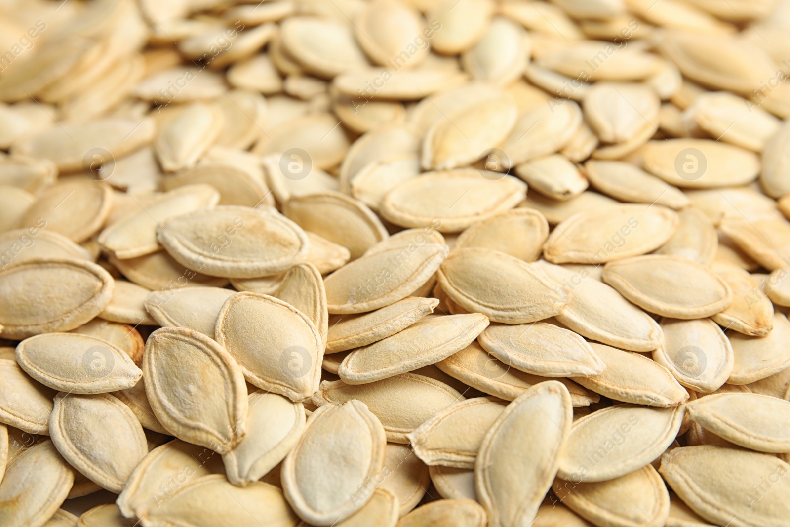 Photo of Raw unpeeled pumpkin seeds as background, closeup