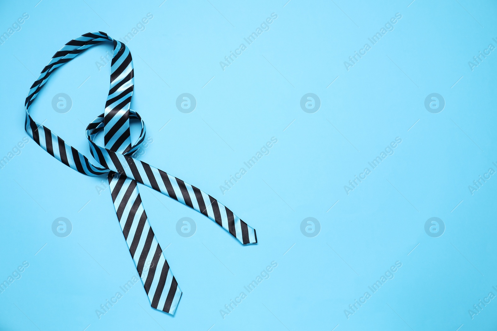 Photo of Striped necktie on light blue background, above view. Space for text