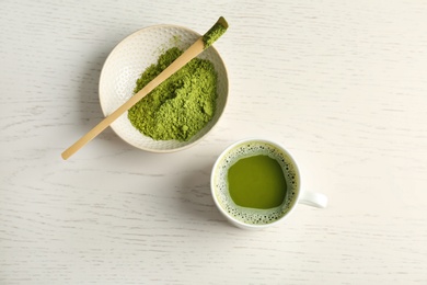 Photo of Cup of fresh beverage and chawan with powdered matcha tea on wooden background, top view