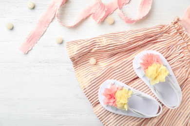 Photo of Pair of cute baby sandals and clothes on table, top view