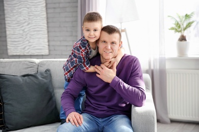 Photo of Dad and his son hugging on sofa at home. Father's day celebration