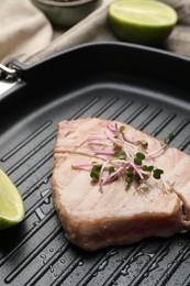 Photo of Delicious tuna steak with lime and microgreens in grill pan, closeup