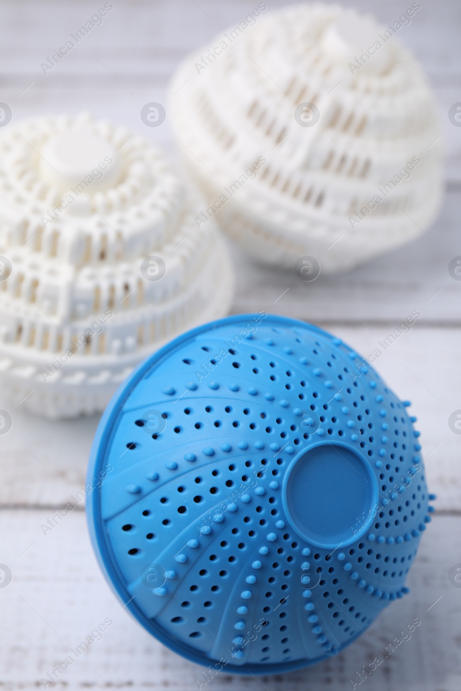 Photo of Dryer balls for washing machine on white wooden table, closeup