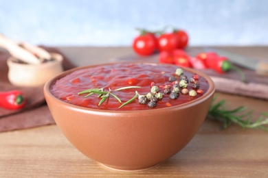 Photo of Bowl of hot chili sauce with rosemary and spices on table, closeup