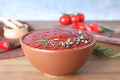 Bowl of hot chili sauce with rosemary and spices on table, closeup